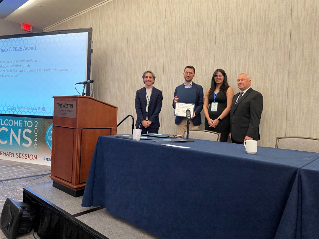 Best of Track 5 award recipient and presenters pose on stage with a certificate.