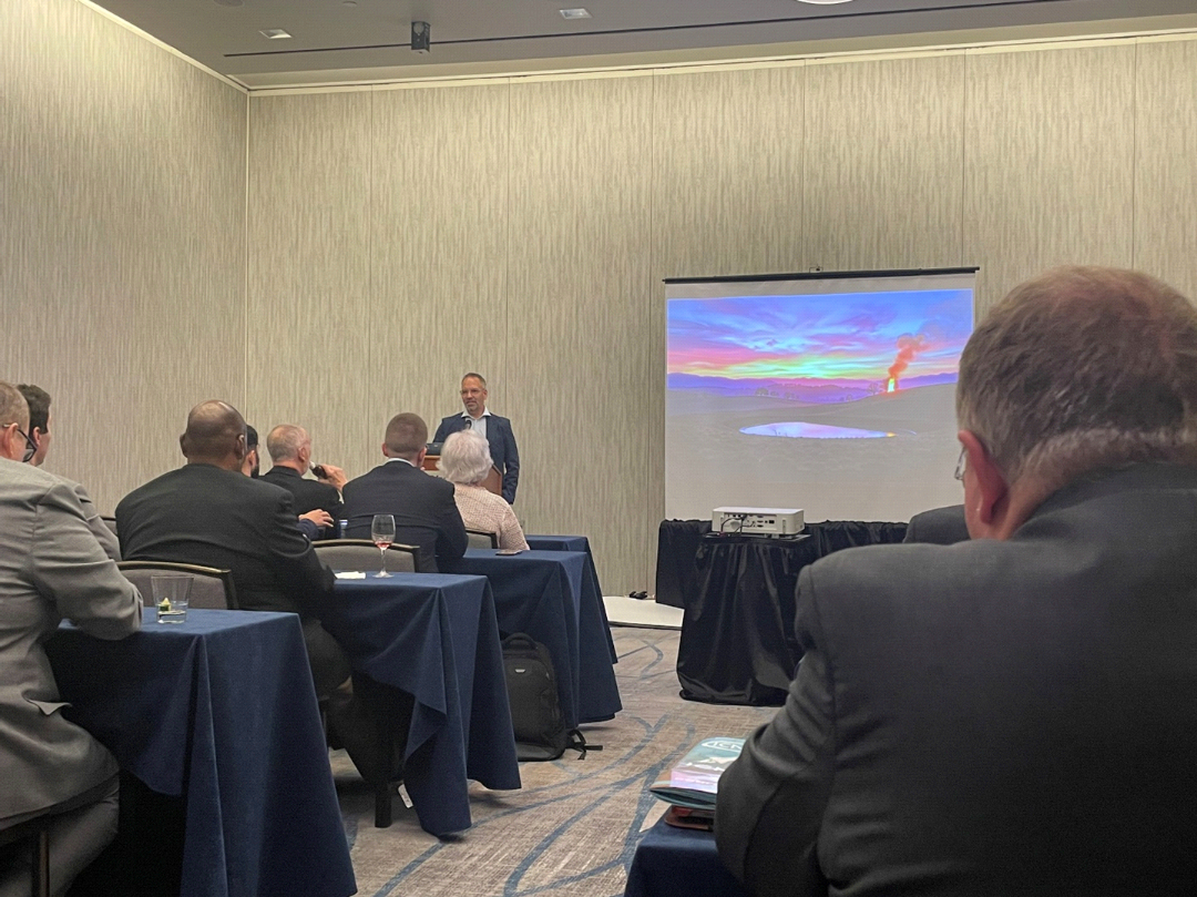 The day 1 evening keynote speaker presents to attendees beside a projected image.