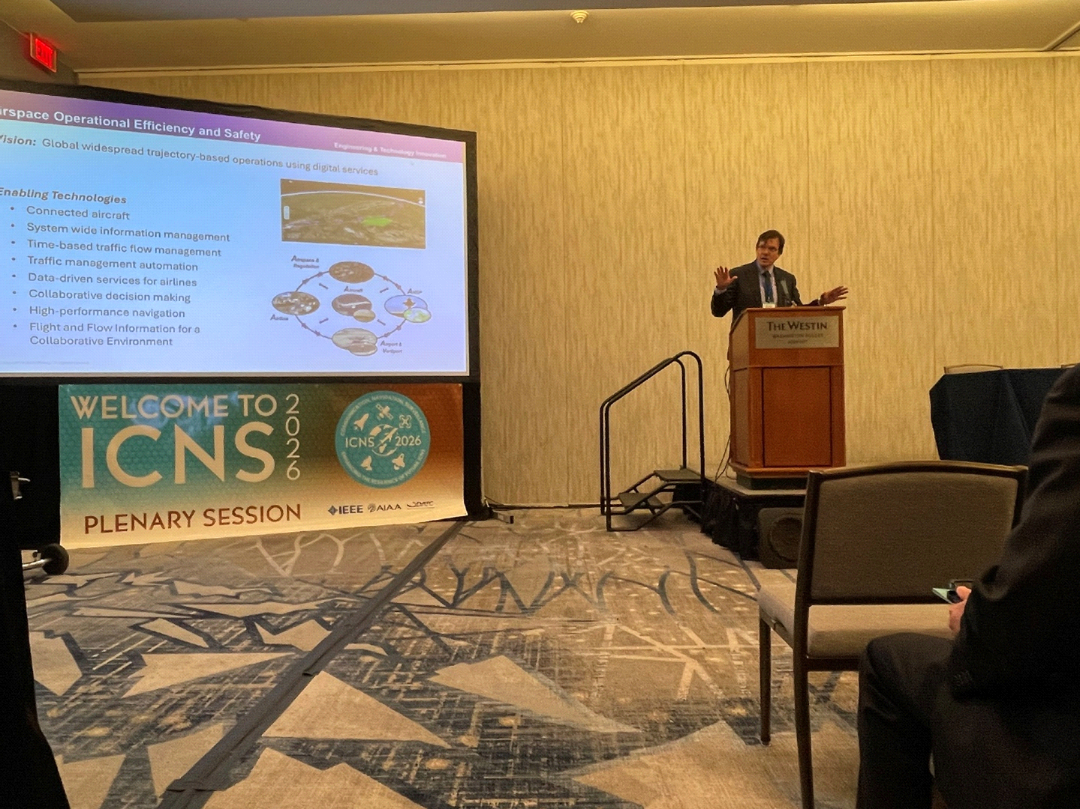 The day 2 keynote speaker presents from the podium beside a slide on airspace efficiency and safety.