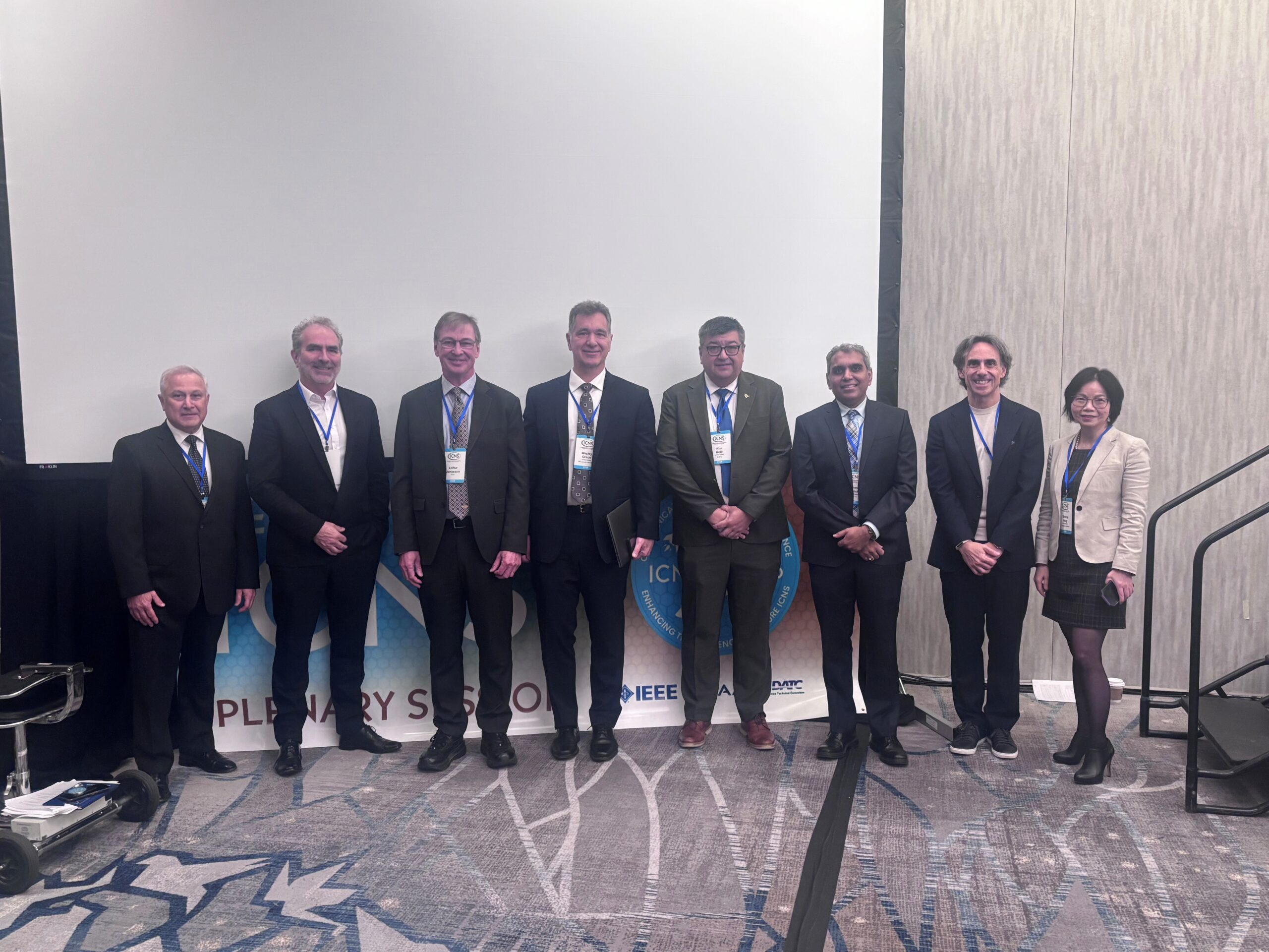 Plenary V participants pose in front of the ICNS 2026 banner image.