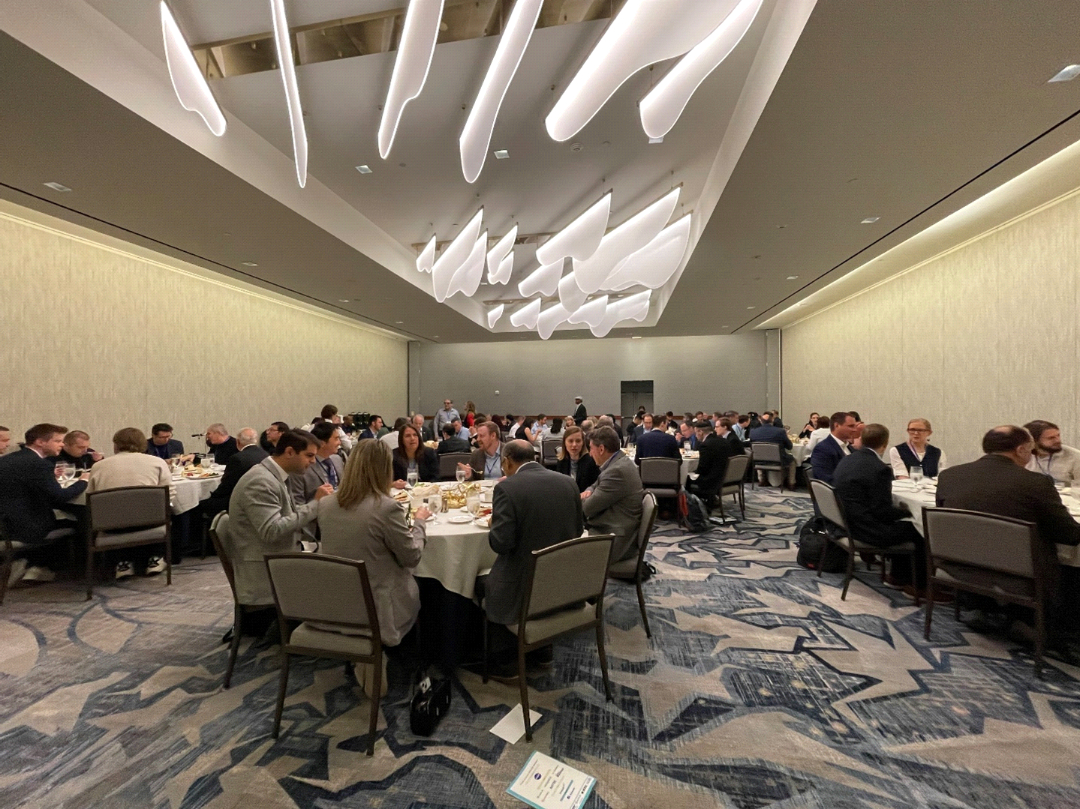 ICNS attendees gather for lunch at round tables in a conference ballroom.